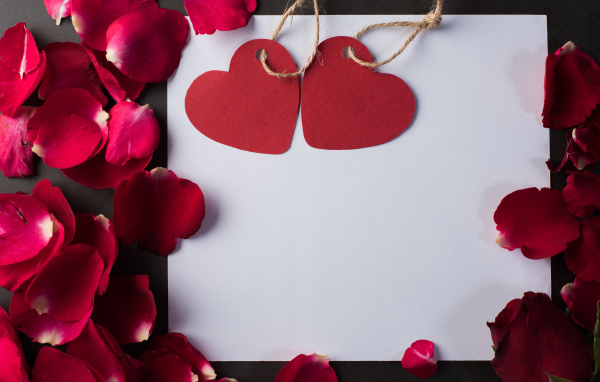 Белый лист бумаги с сердечками и лепестками роз 