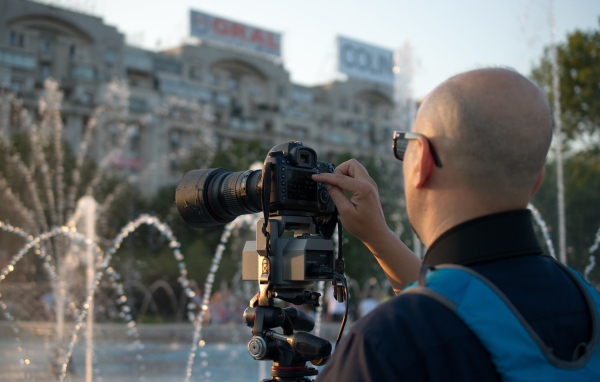 Мужчина снимает на камеру фонтан в парке