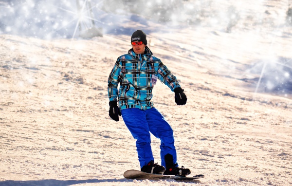 Мужчина сноубордист съезжает с горы 