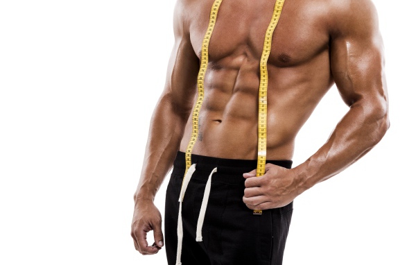 Накаченное тело спортивного мужчины с сантиметром на белом фоне