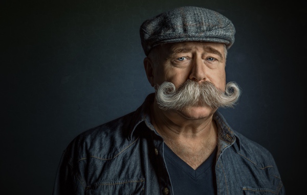 Мужчина в кепке с большими усами на лице 