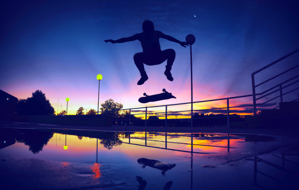 Парень прыгает на скейте на фоне заката