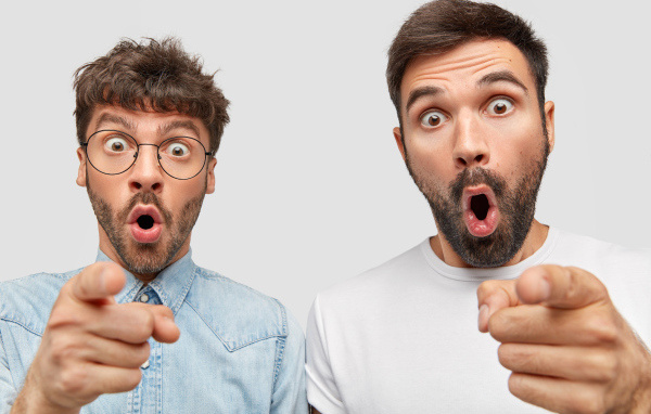 Два удивленных мужчины на сером фоне