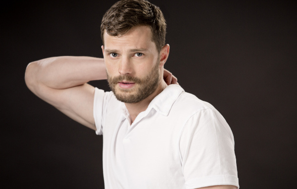 Актер Джейми Дорнан в белой рубашке на коричневом фоне