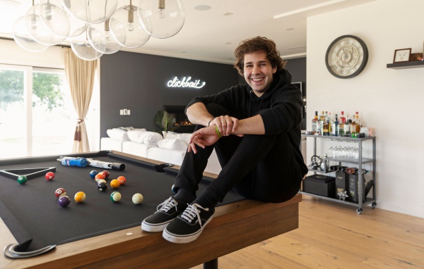 Молодой блогер, юморист  Дэвид Добрик сидит на столе