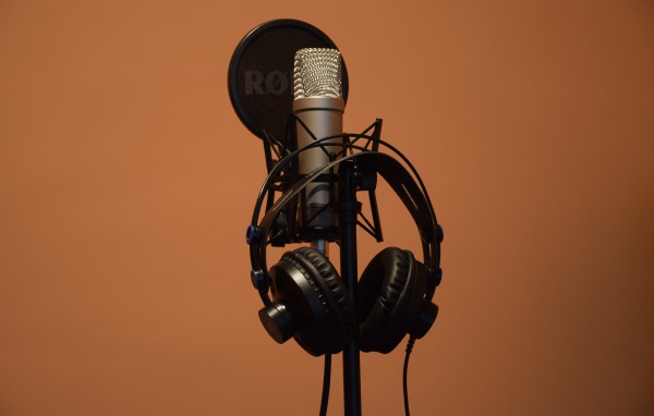 Конденсаторный микрофон с наушниками на коричневом фоне
