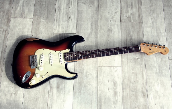 Электрогитара лежит на деревянном полу