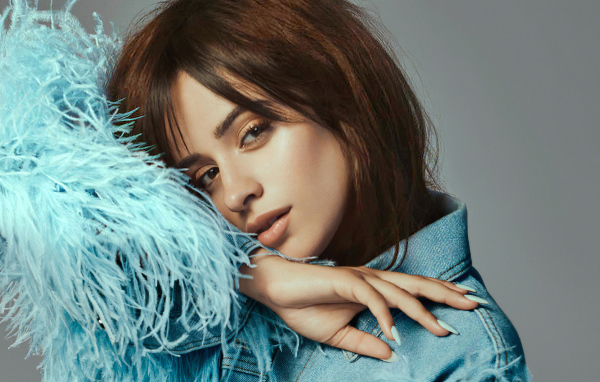 Певица Камила Кабельо в джинсовой куртке на сером фоне