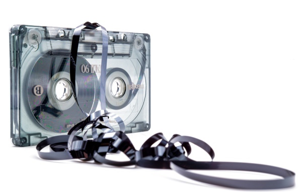 Магнитофонная кассета в размотанной пленкой на белом фоне