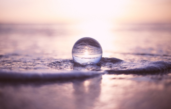 Прозрачный стеклянный шар лежит на пене в море
