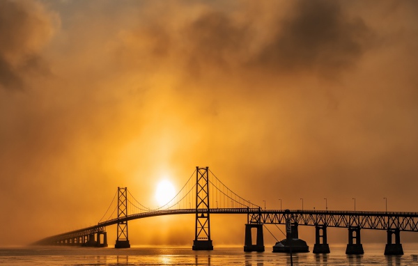 Мост через реку в тумане на восходе солнца