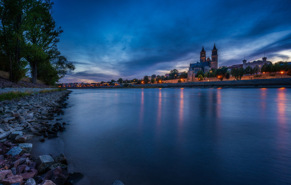 Замок у реки на фоне неба в сумерках 