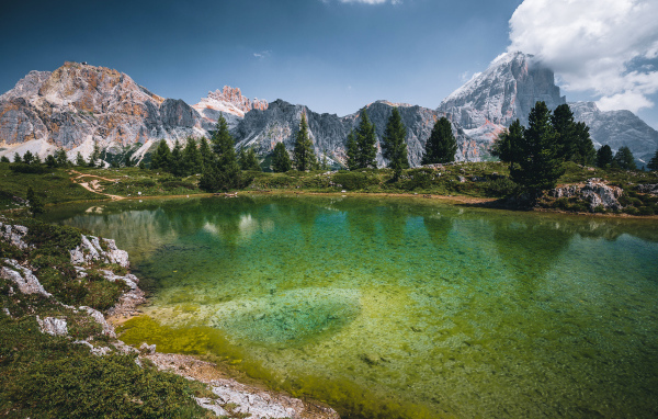 Озеро у заснеженных гор под небом с белыми облаками