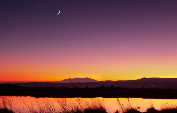 Молодой месяц в небе над озером ночью 