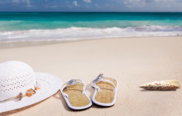 Сланцы, шляпа и ракушка на песке у моря 