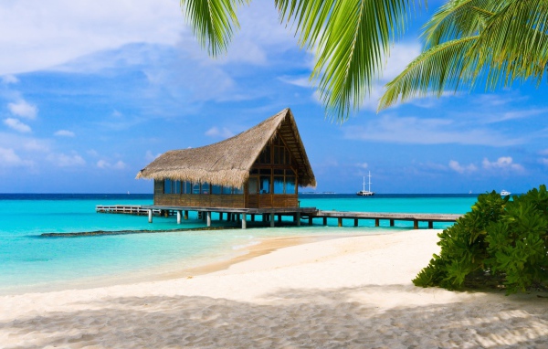 Дом на сваях на берегу тропического пляжа с белым песком