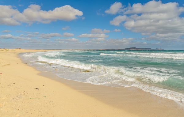 Бушующие морские волны на желтом горячем песке 