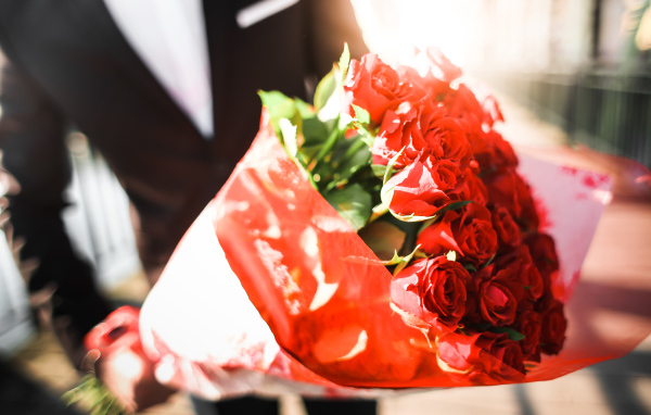 Большой красивый букет красных роз в руках мужчины 