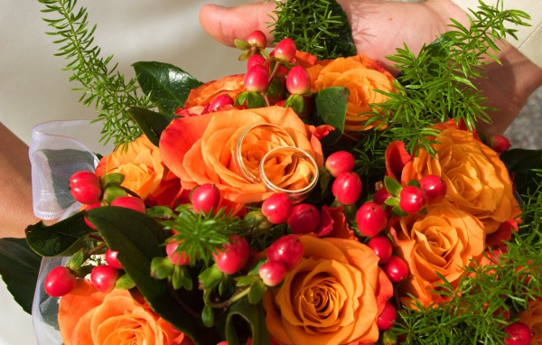 Букет оранжевых роз с красными ягодами и обручальными кольцами