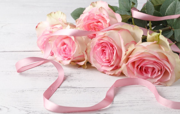 Букет розовых роз с лентой на белом столе 