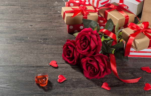 Букет красных роз и подарки на столе 