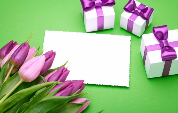 Букет тюльпанов на столе с листом бумаги и подарками 