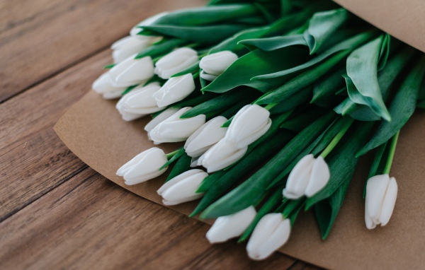 Большой букет белых тюльпанов в бумажном пакете 