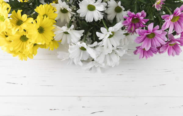 Желтые, белые и розовые хризантемы на белом деревянном столе