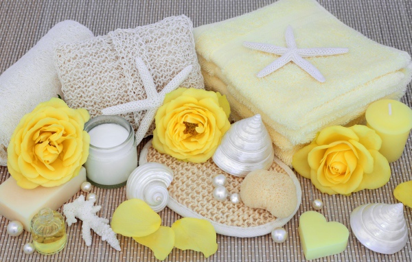 Желтые розы на столе с полотенцем, ракушками и мылом