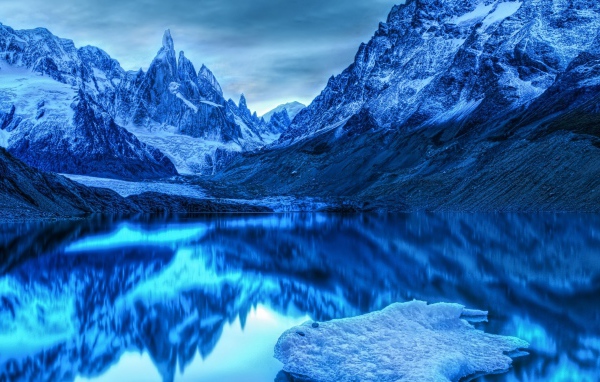 Голубой холодный закат на заснеженными горами у озера 