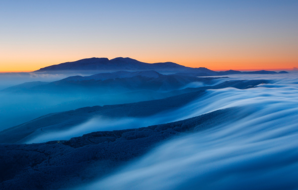 Туман покрывает высокие горы на рассвете 