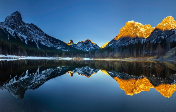 Mountain peaks in the sun are reflected in the lake