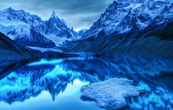Заснеженные горы отражаются в воде в сумерках