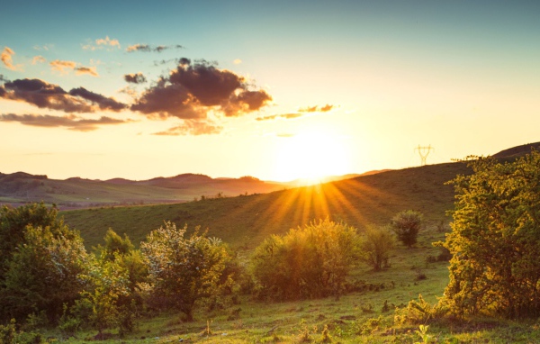 Яркое летнее солнце встает из-за гор 