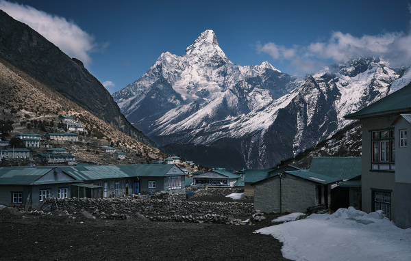 Поселок на фоне заснеженных гор под голубым небом 