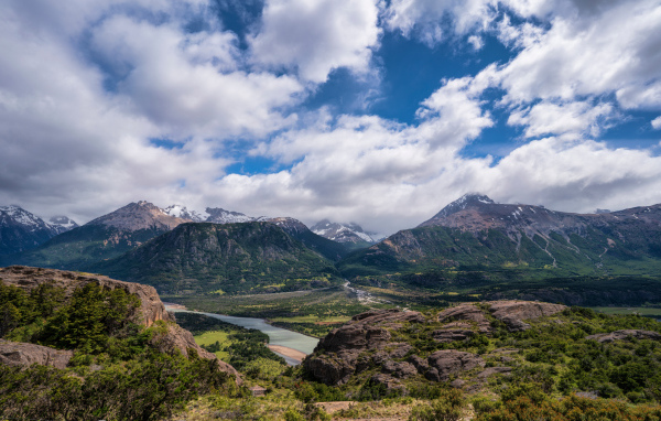 Белые облака в голубом небе над покрытыми зеленью горами