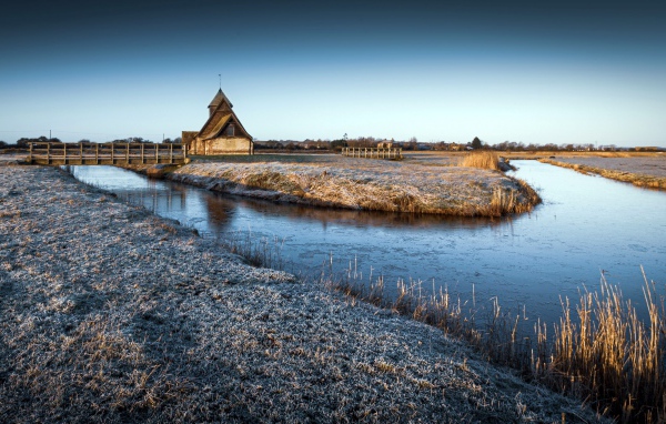 Иней покрывает землю холодным утром у реки