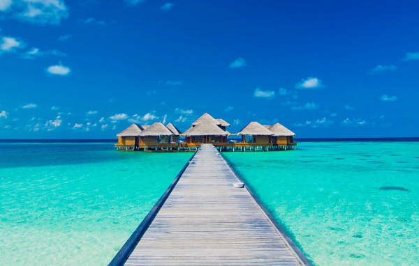 Деревянный мост к домам на сваях в голубом океане 