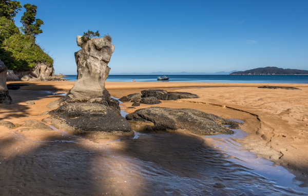 Большие камни на берегу на мокром песке у моря летом 