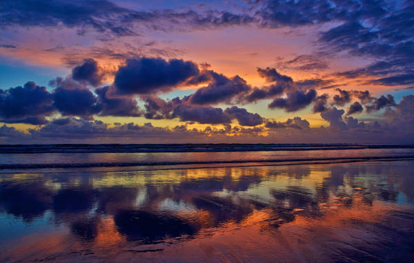 Черные тучи отражаются в морской воде на закате