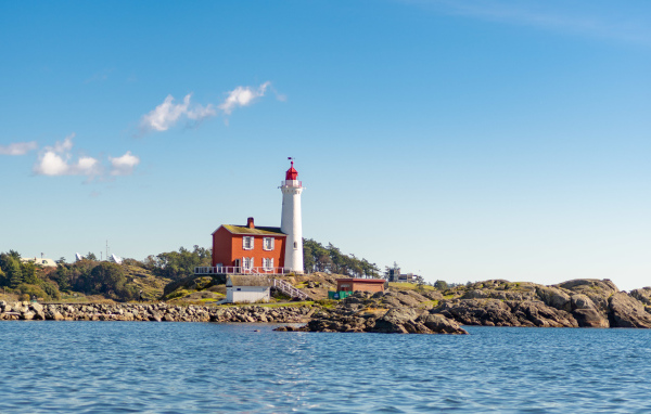 Маяк на каменном берегу моря под голубым небом 