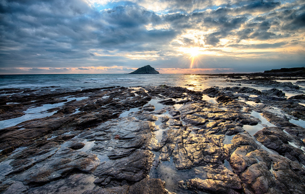Каменный берег океана в лучах солнца