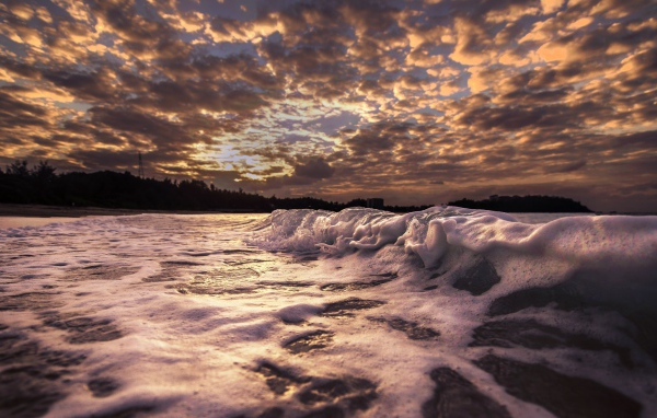 Белые волны на песке на рассвете 