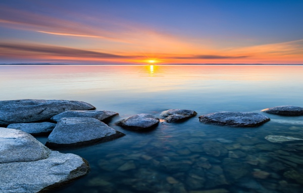 Большие камни в воде на закате яркого летнего солнца 