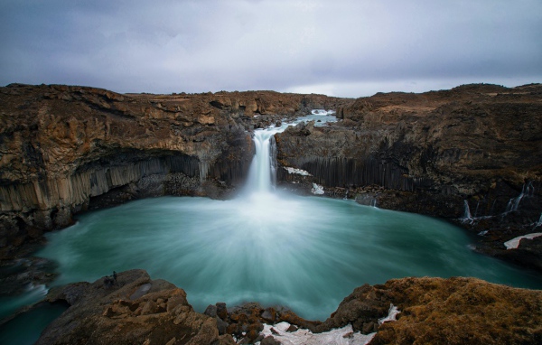 Красивый водопад стекает с каменной скалы в озеро 