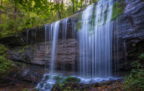 Холодная вода водопада стекает по мокрой скале