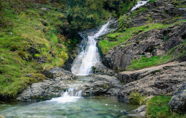 Горный ручей стекает по камням в реку 