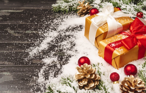 Два новогодних подарка на столе с еловыми ветками 