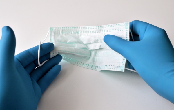Руки в медицинских перчатках держат маску 