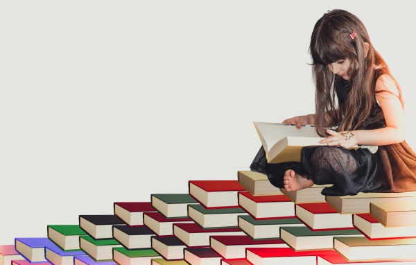 Маленькая девочка сидит на горе книг 